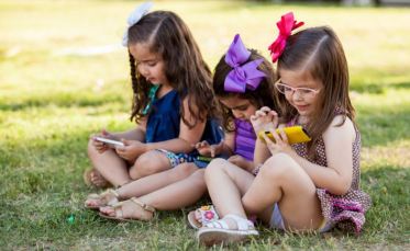 Cute-Little-Girls-Playing-With-Their-Smartphones-Ignoring-One-Another-In-A-Park-Social-Media-And-Technology-Effect